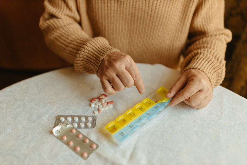Persona mayor organizando su medicación en un pastillero semanal